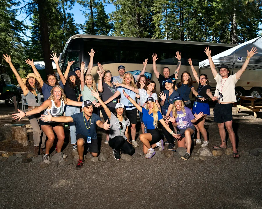 Camp Rennervation staff and volunteers cheering together in front of the foundation bus
